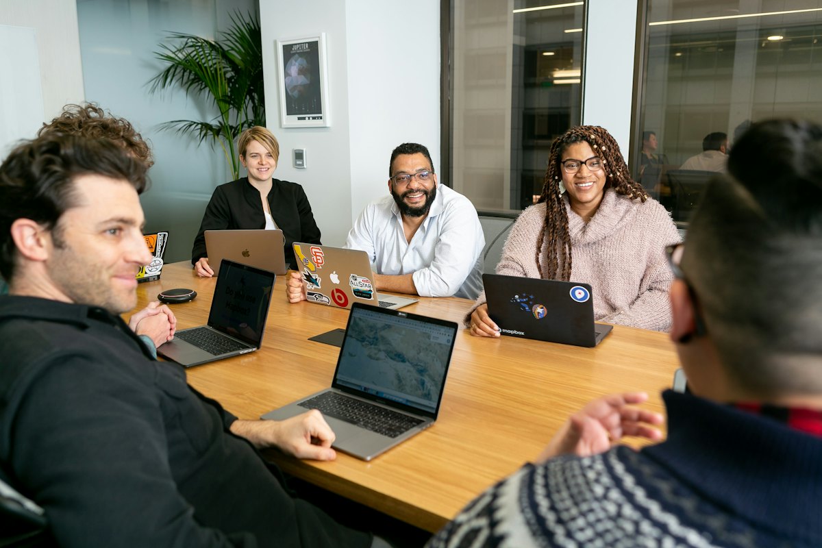 Equipe trabalhando com laptops em uma mesa de reunião